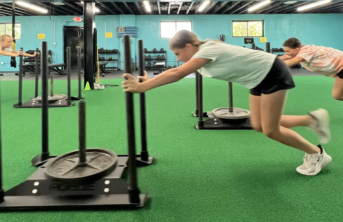 Athletes pushing weighted sleds on the turf at RAF